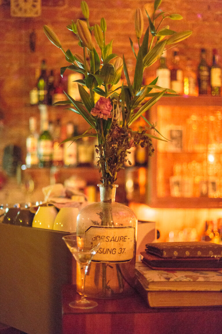 ein Apothekergefäß mit Lilien davor ist ein Martini Cocktail