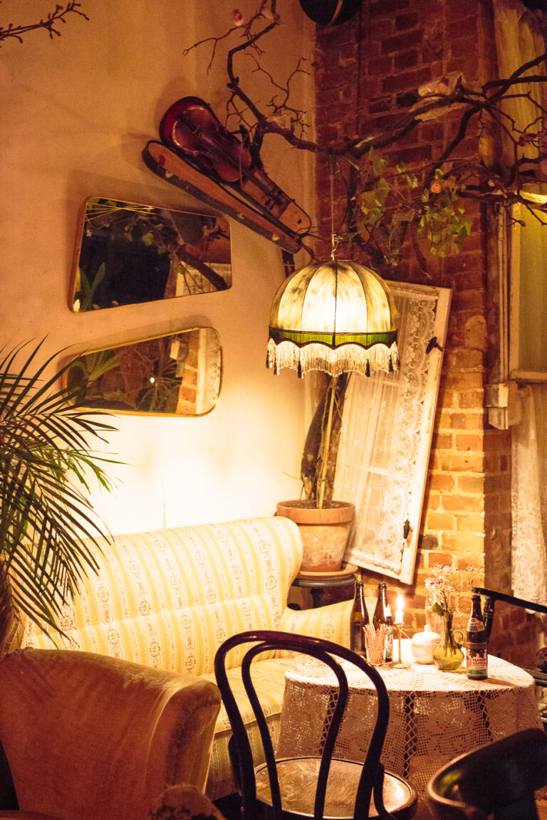 Sitzecke mit Sofa. an der Wand sind Spiegeln und eine Lampe hängt von einem großen Ast