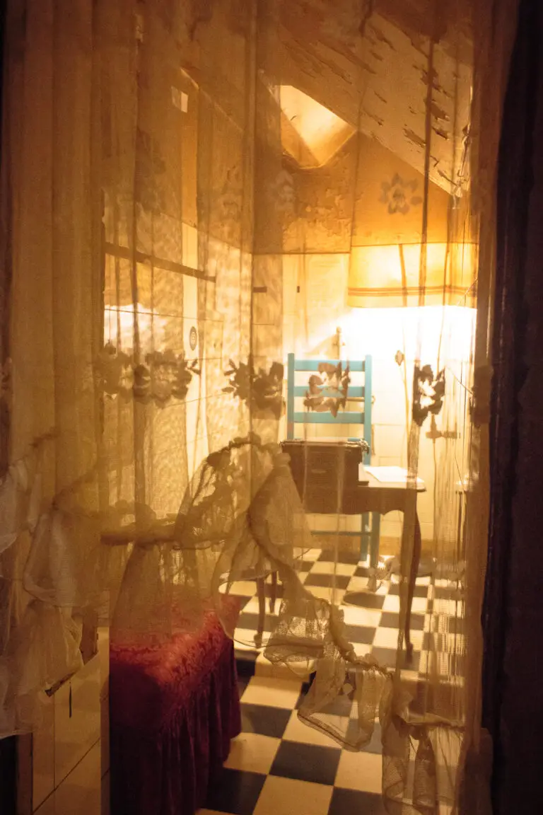 das gefundene verlorene Zimmer mit Vorhang. Darin befindet sich ein Stuhl mit kleinem Tisch und eine Schreibmaschine