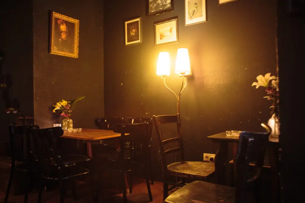 dunkle Sitzecke mit Stühlen - an der Wand eine Bildergalerie und eine Stehleuchte